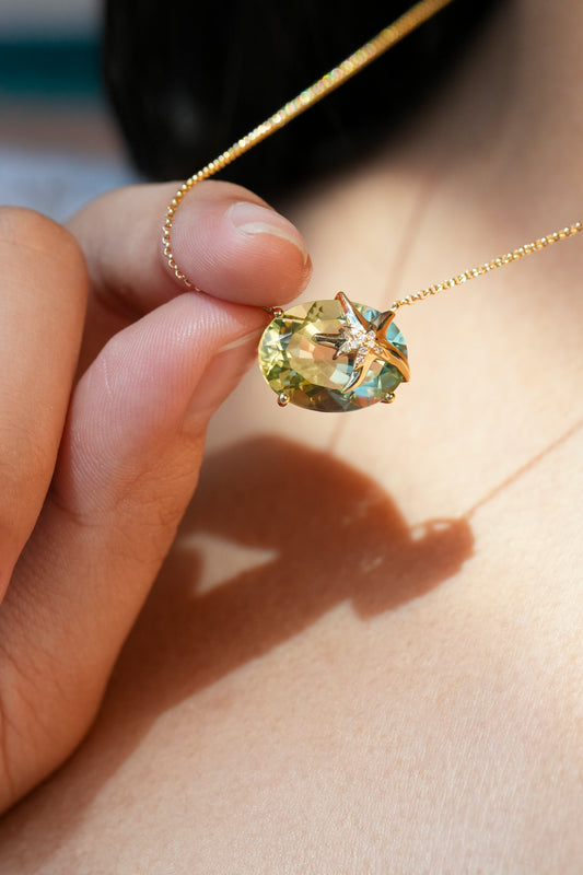 Worn gold necklace with a large green Prasiolite and gold starfish with diamond accents shown by a hand - 774227