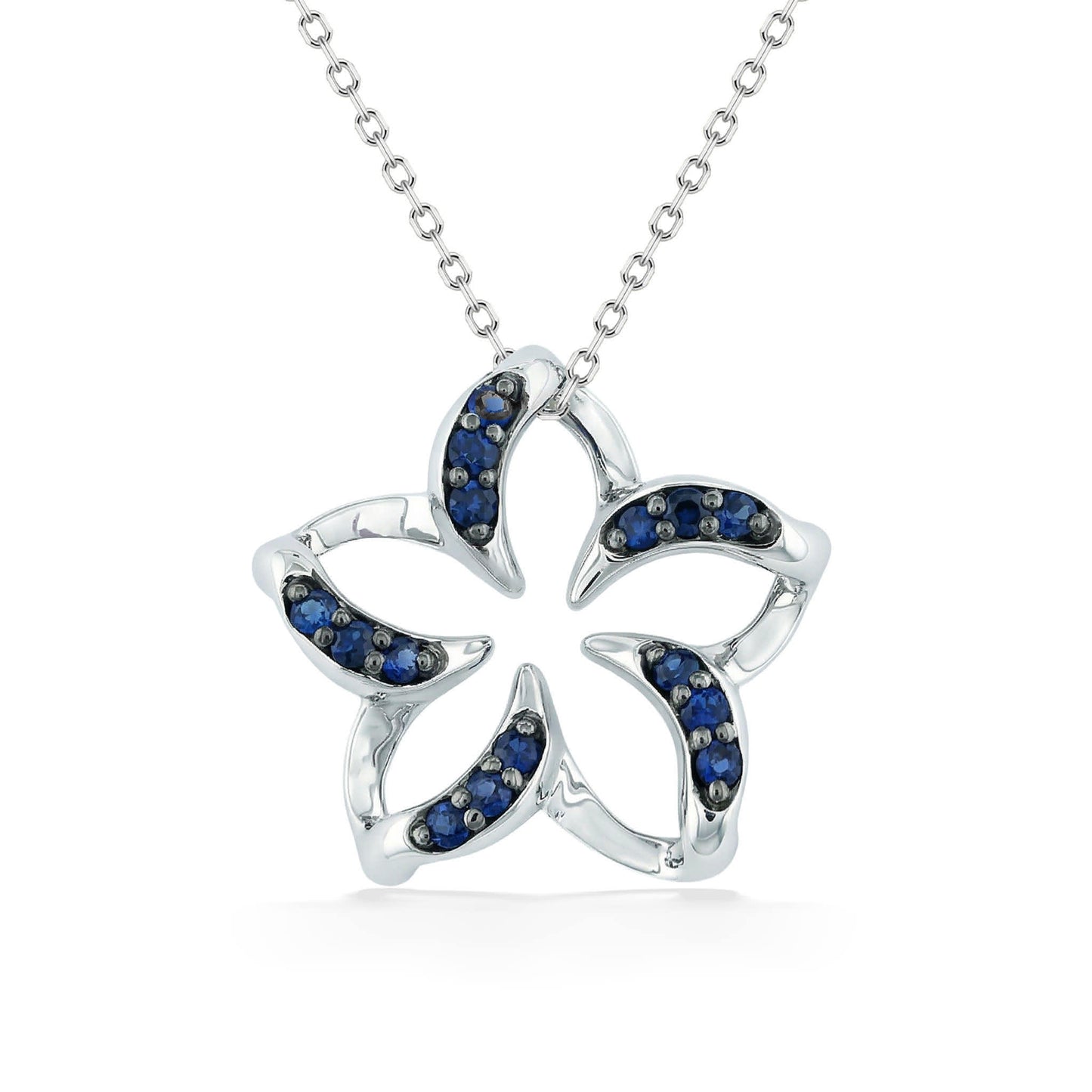 Polished white gold plumeria pendant with negative space center & blue sapphire lined curved petals. Item No. 19241