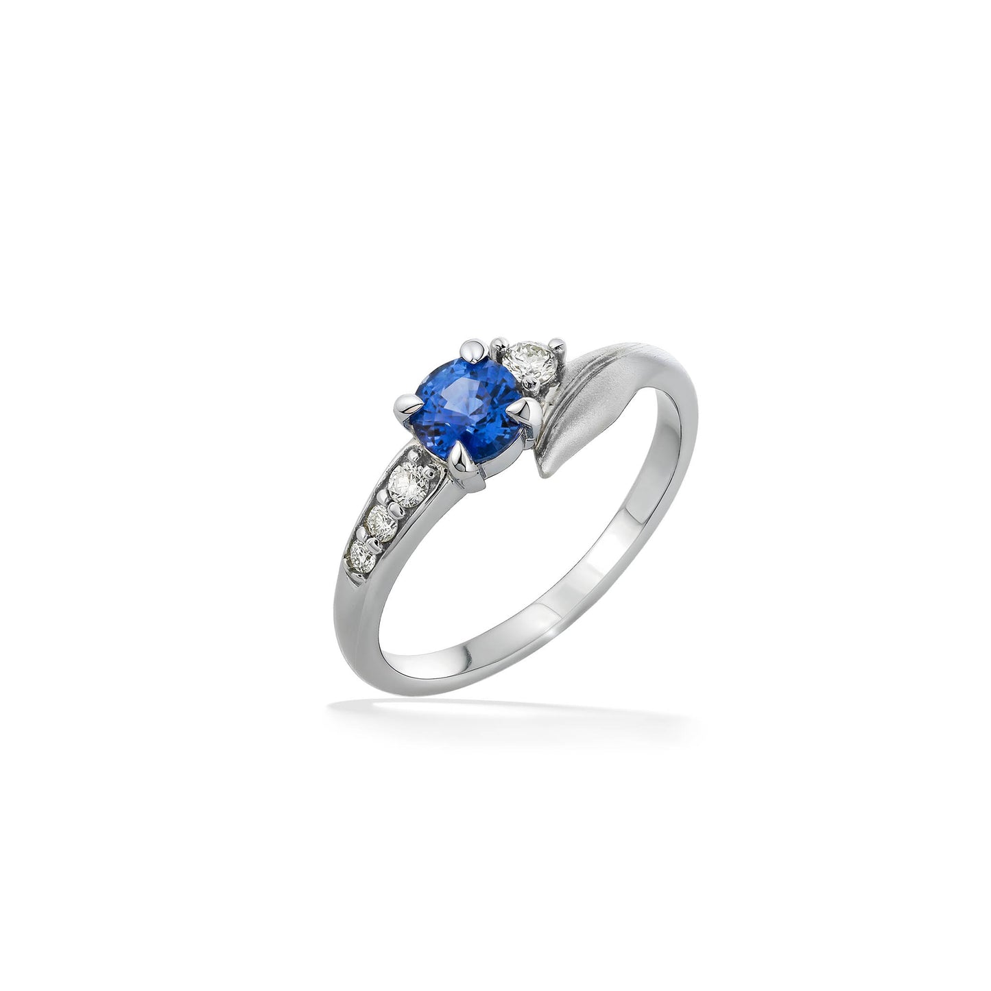 White gold leaf ring with blue sapphire center and diamond accents in a flowing nature inspired design. Item No. 44385