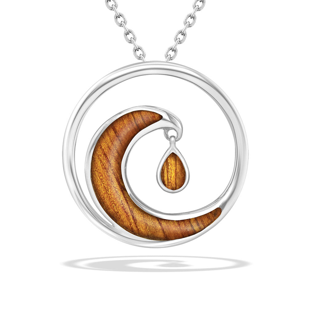 Sterling silver circle pendant with a koa wood inlay shaped like a cresting wave with a dangling koa shimmer. Item No. 768677