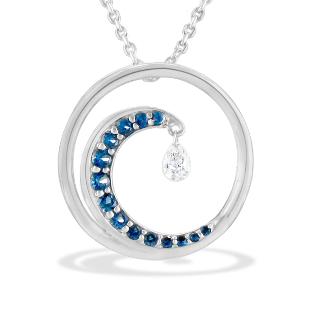 White gold circle pendant with a blue sapphire-lined crest resembling a wave, dangling a shimmer diamond. Item No. 19242