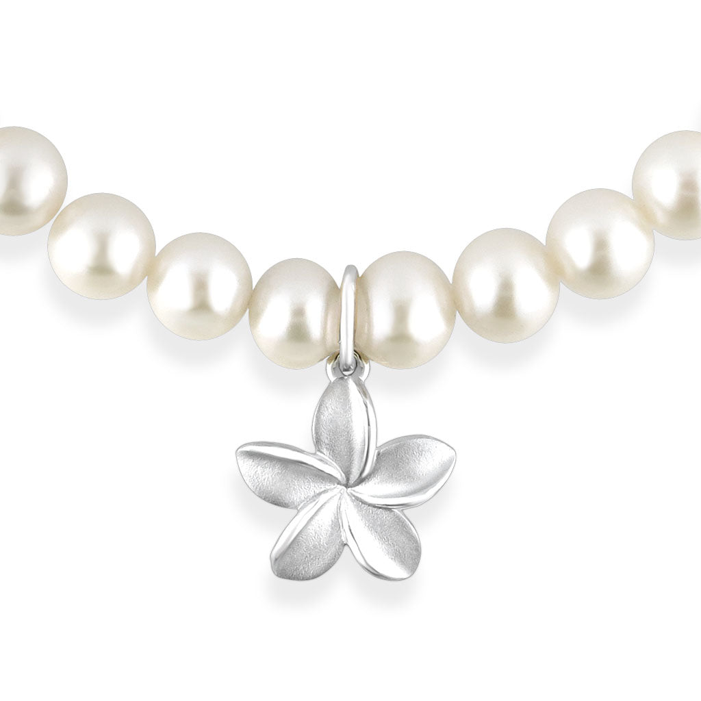 Focused view of the sterling silver Plumeria charm on the white freshwater pearl bracelet. Item No. 41521