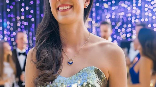 model wearing Na Hoku Horizon jewelry and gold glitter dress at party; other guests in background talking