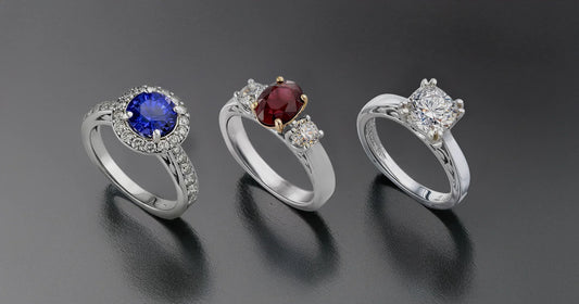 Three white gold engagement rings with gemstones on a dark background