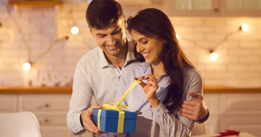 Man and woman opening a gift together in a cozy indoor setting