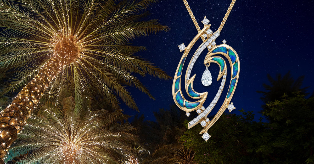 Yellow gold Laniakea pendant with opal inlay and diamond shaped accents against night sky background and palm trees with Christmas lights