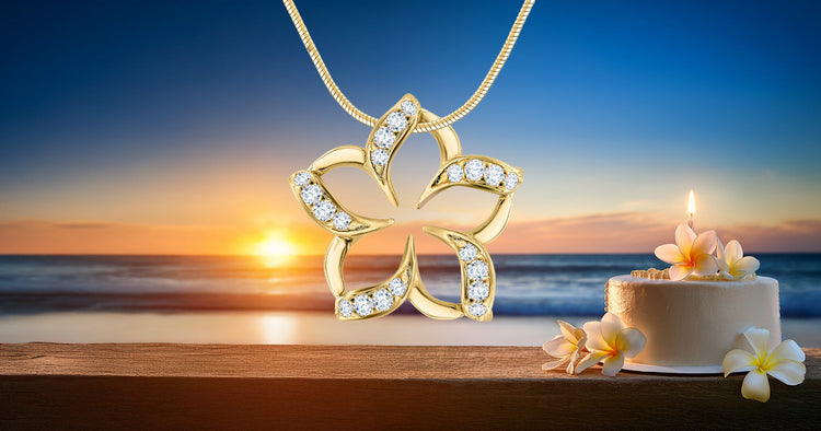 Gold Floating Plumeria Pendant with Diamonds and birthday cake with flowers against beach sunset