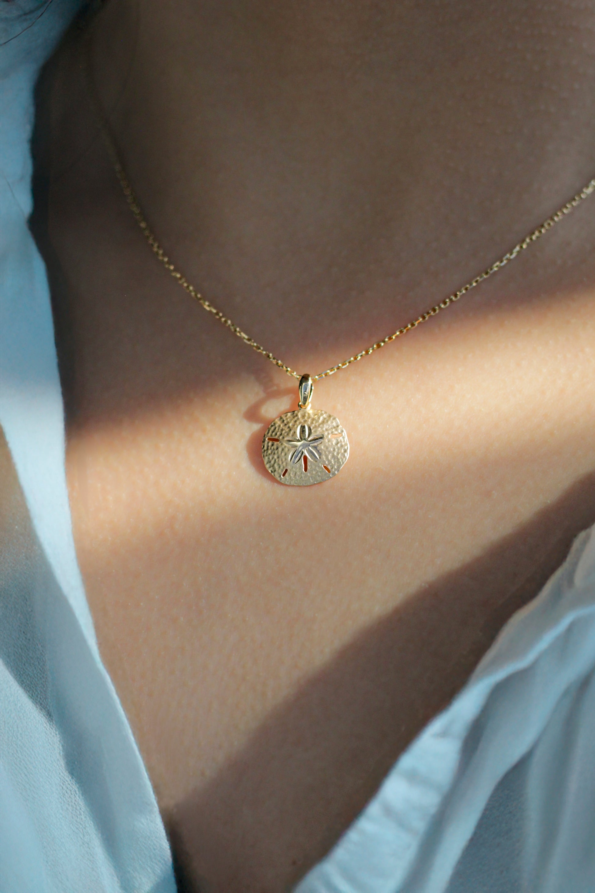 Model wearing a gold necklace with a small Sand Dollar charm - 19202
