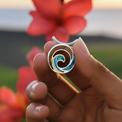 Hand holding silver and gold wave pendant with Koa and blue-green Abalone inlay against blurry floral background. Item No.44265