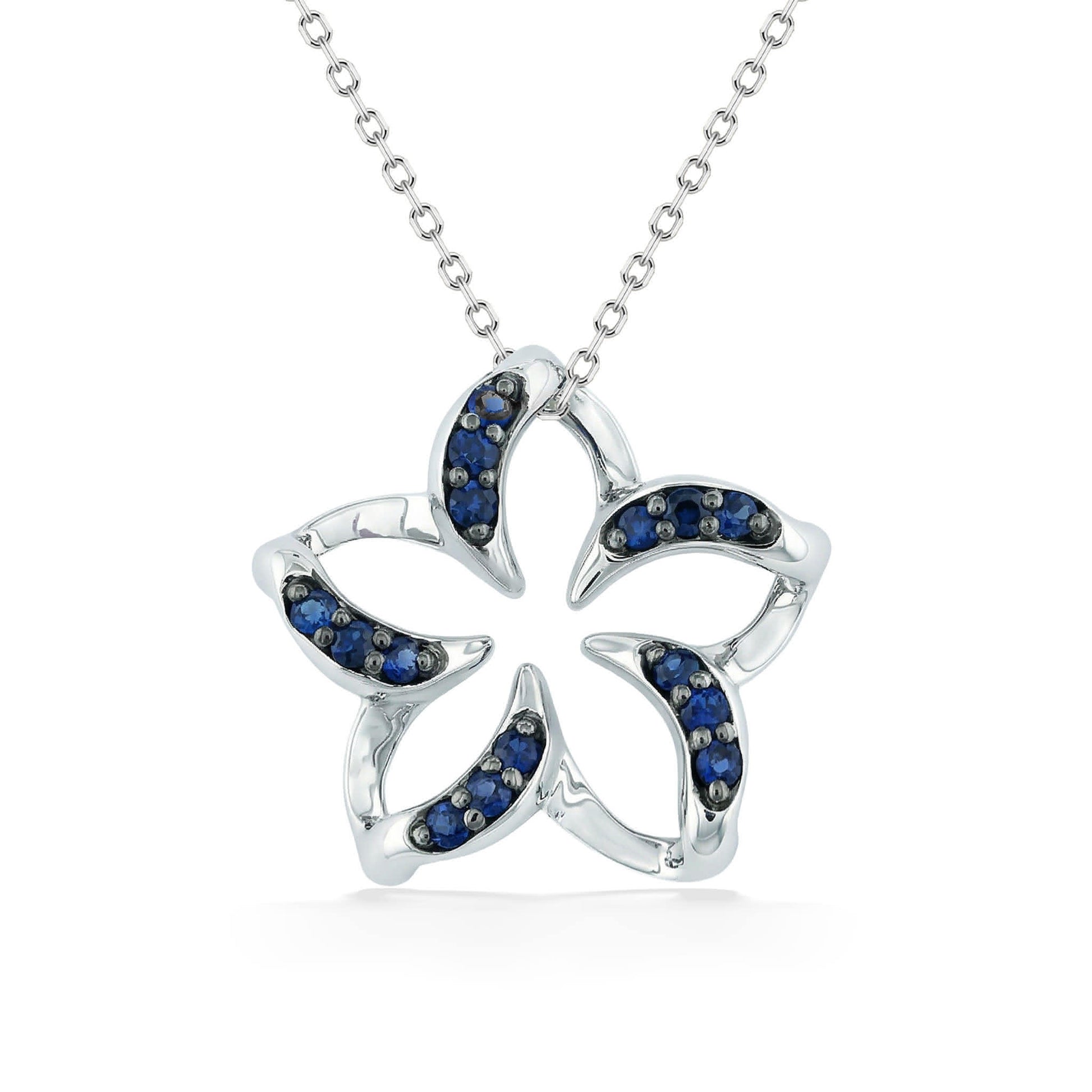 Polished white gold plumeria pendant with negative space center & blue sapphire lined curved petals. Item No. 19241