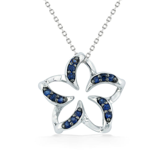 Polished white gold plumeria pendant with negative space center & blue sapphire lined curved petals. Item No. 19241