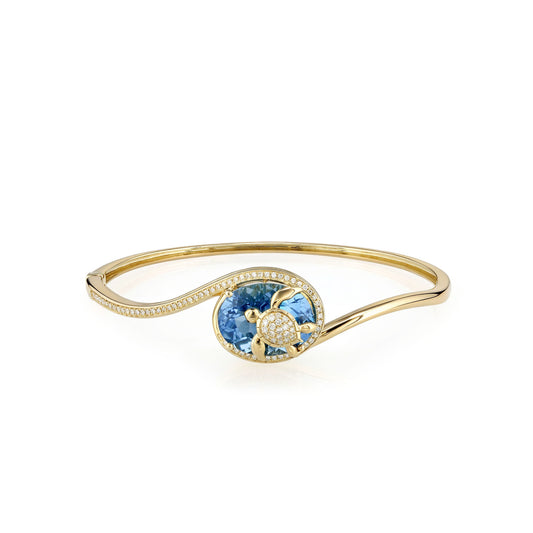 Yellow gold hinged bangle with blue topaz turtle center & diamond accents flowing on a curved wave design. Item No. 774326